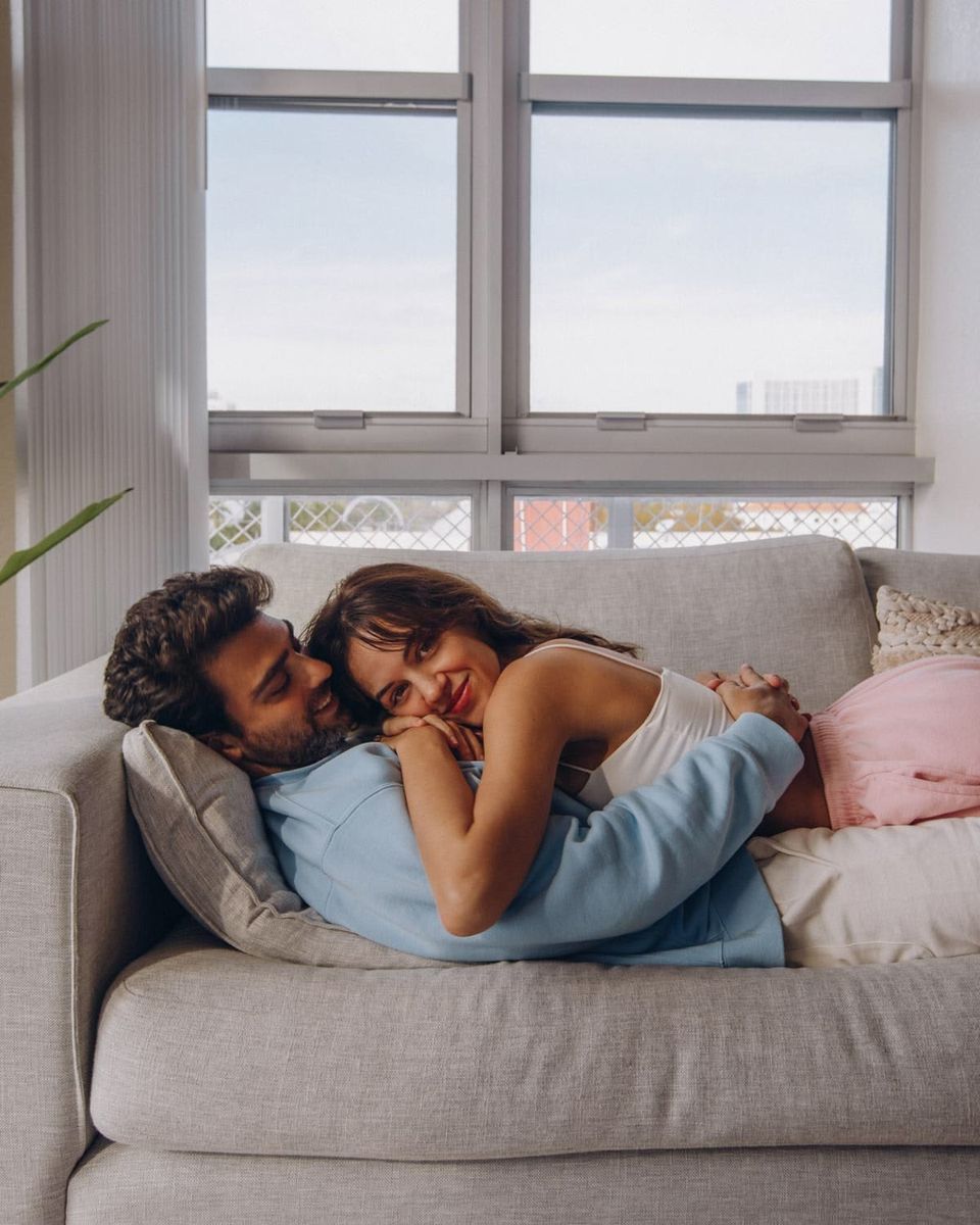 A smiling couple lying close together on a sofa
